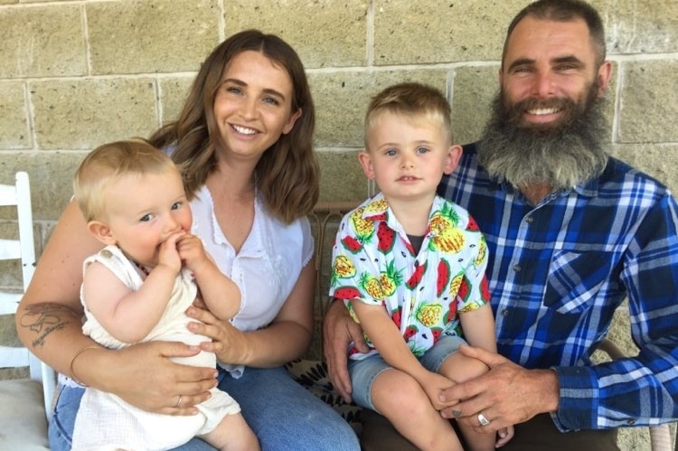 Mother and father sitting together with their baby and toddler on their laps.