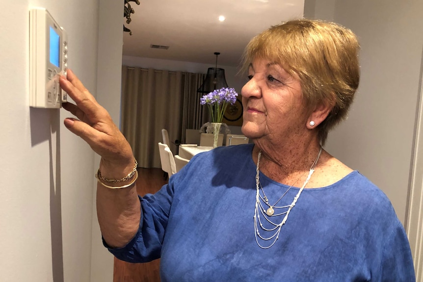 Wendy Farmilo places her hand on the air conditioning controls on the wall of her home