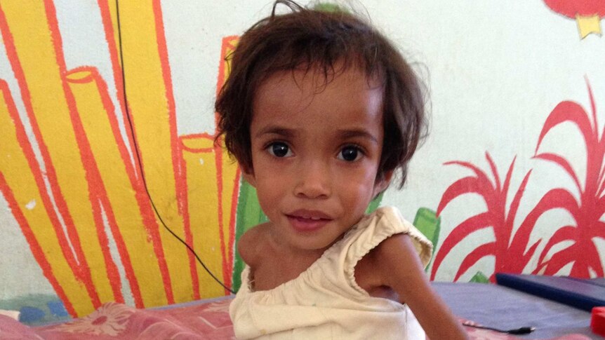 Small, malnourished girl on hospital bed.