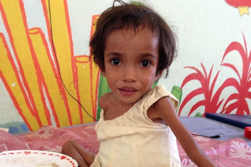 Small, malnourished girl on hospital bed.