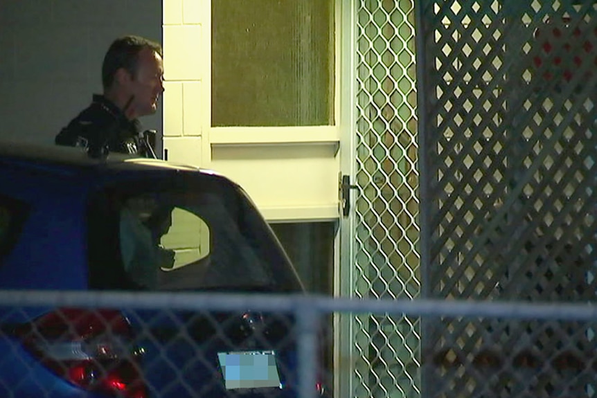 A policeman outside a Cairns house at night, responding to a shooting incident