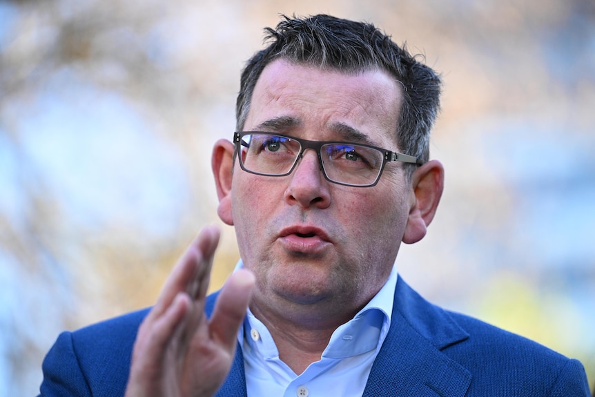 Victorian Premier Daniel Andrews makes a hand gesture at a press conference. He is outdoors