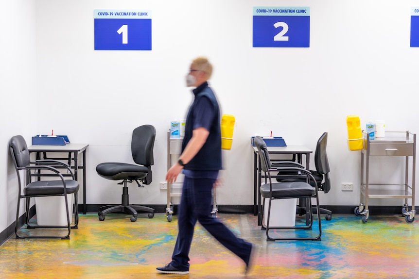 A medical staff walking through a temporary clinic with chairs set up for vaccinations