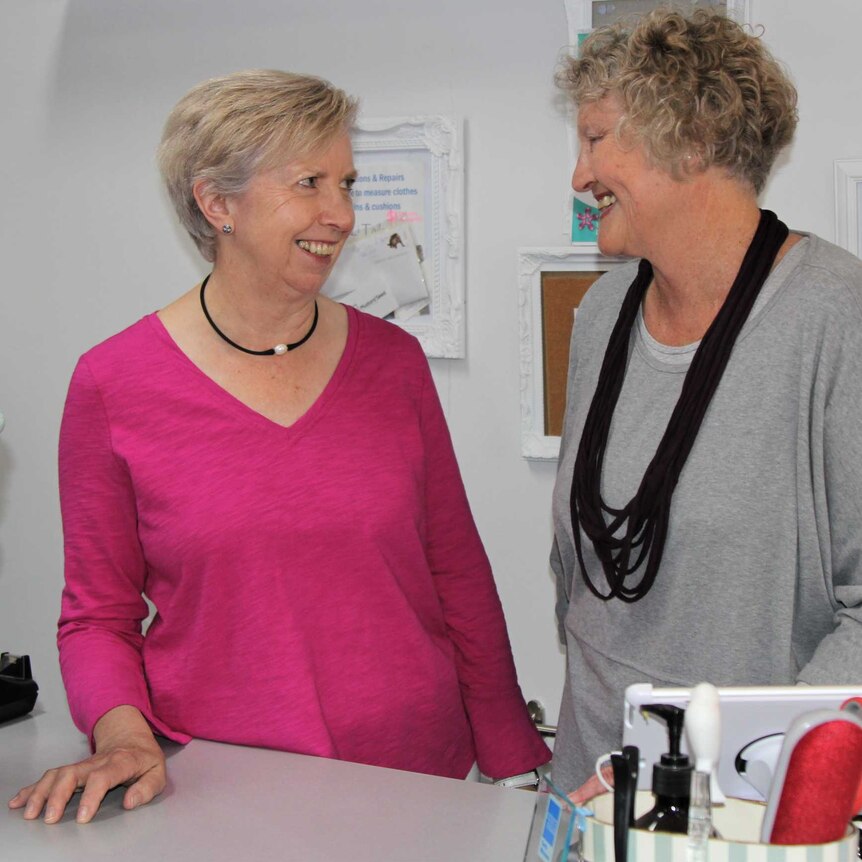 Two women look at each other, smiling.