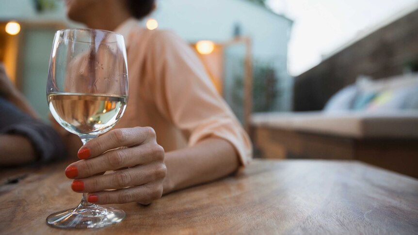 Woman holds glass of white wine.