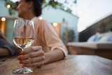 Woman holds glass of white wine.