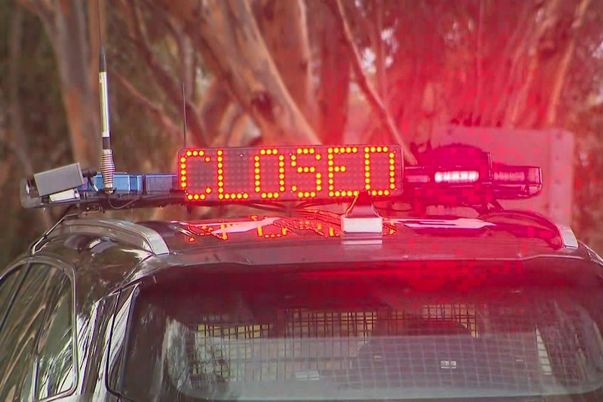 A police vehicle with the word 'CLOSED' on the top of the car in red neon writing