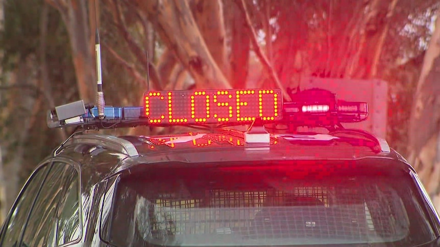 A police vehicle with the word 'CLOSED' on the top of the car in red neon writing