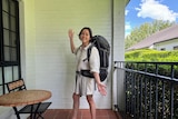 Camellia Aebischer poses on a balcony wearing a large backpack, ready to travel to Asia after taking time off work.