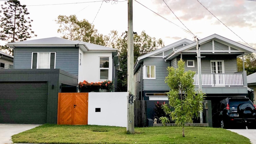 Two grey houses side-by-side in a suburb with a car out the front.