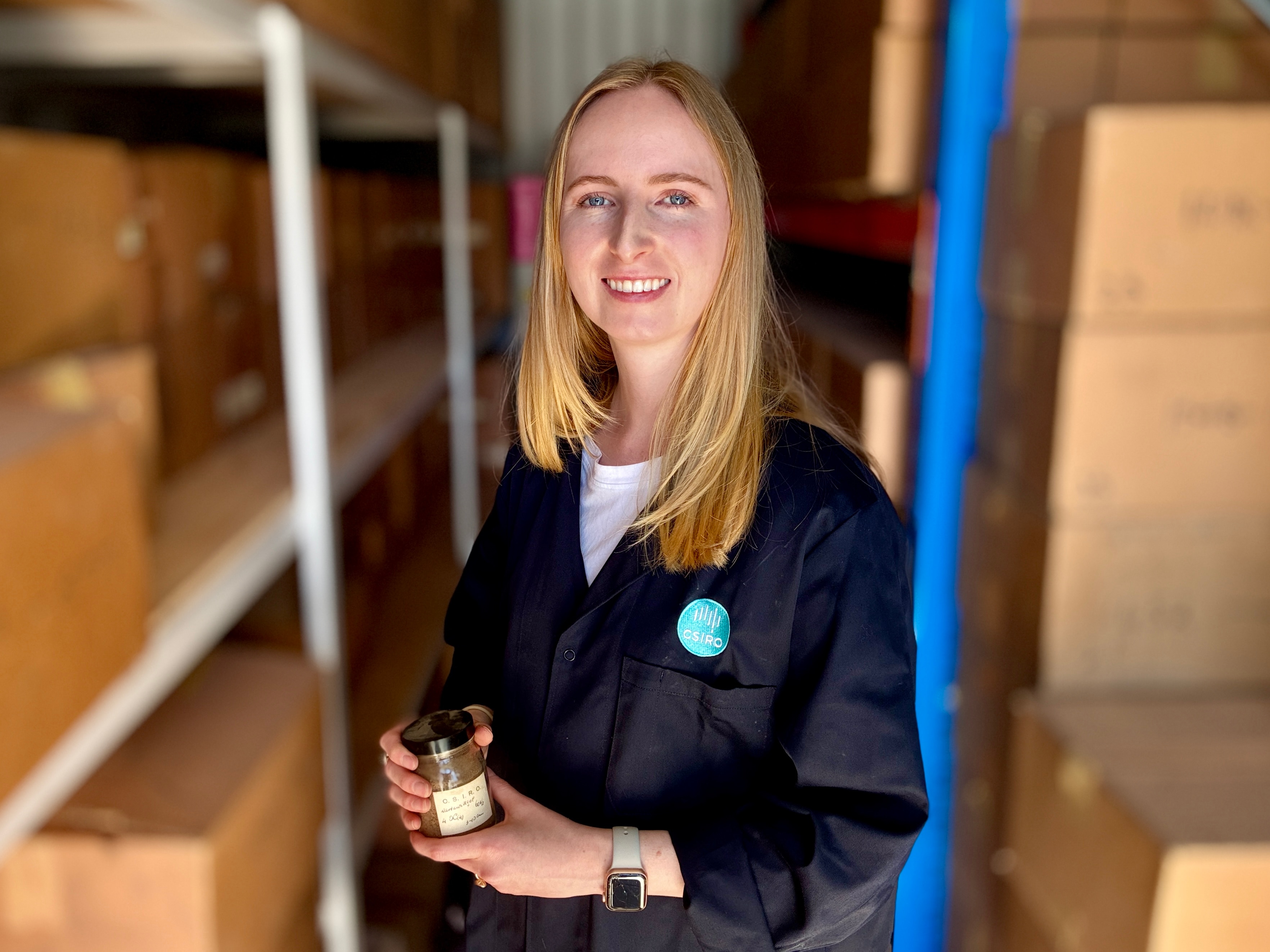 A woman smiles as she holds a sample of soil.