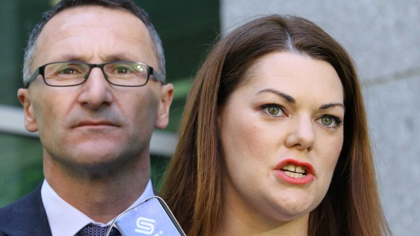 Greens Leader Richard Di Natale listens to Greens senator, Sarah Hanson-Young, at a press conference.