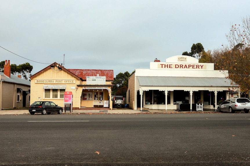 A side view of a quiet country street with a line of shops visible