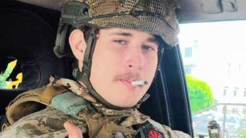 A young man wearing camouflaged clothing with a cigarette in his mouth