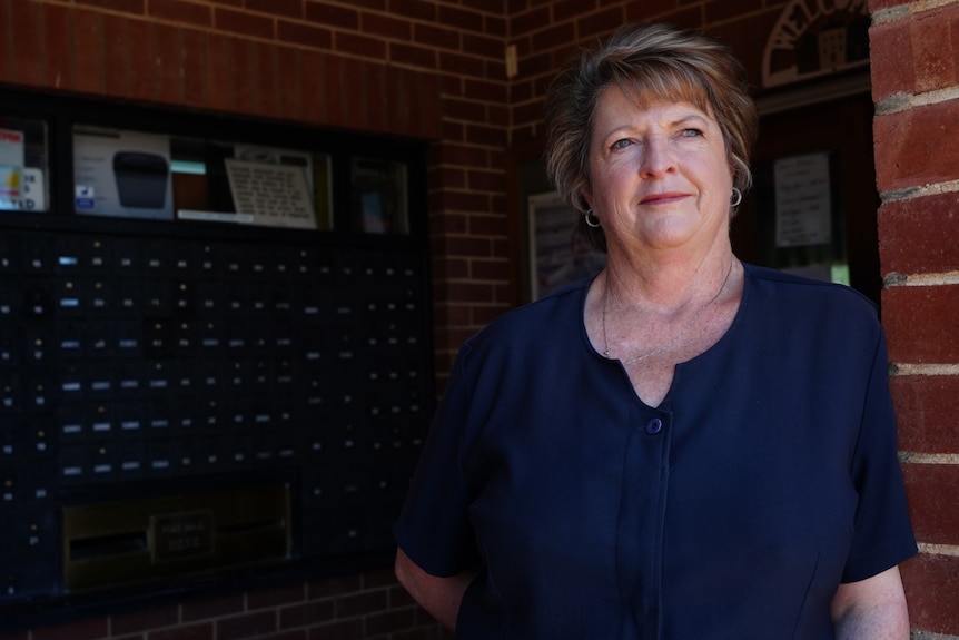 Woman leaning against a brick wall at a post office.