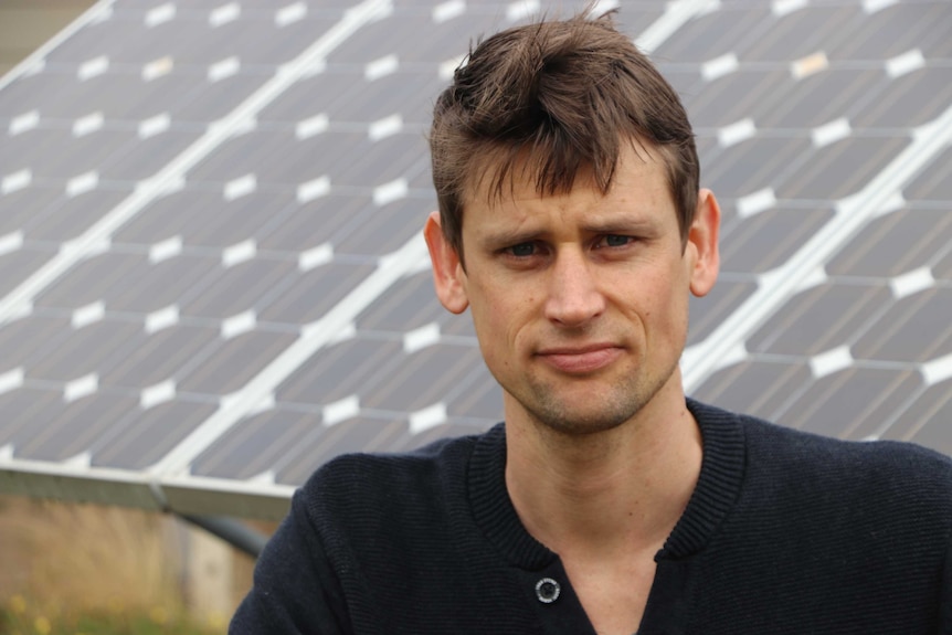 Paul in front of a bank of solar panels.