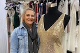 Young woman with short blonde hair smiling while standing amongst an array of formal dresses in her small Wagga Wagga studio.