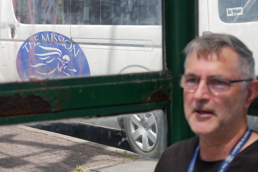 Man in foreground with focus on bus and mission to seafarers logo in the background