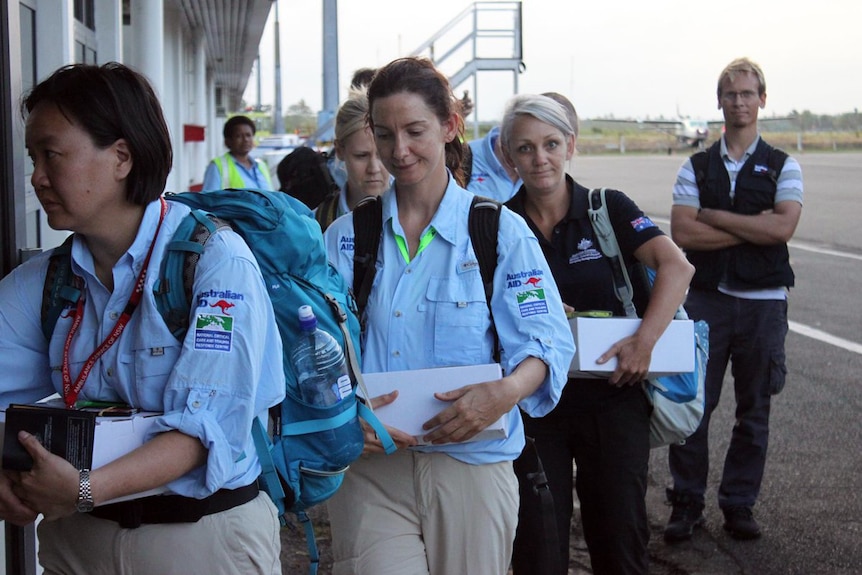 Medical response personnel walking from a plane on the tarmac at an airport in Fiji