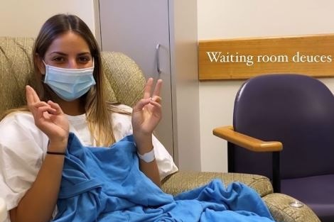 A woman sits in a chair with a sheet over her