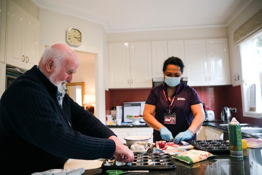 Michael Planck and Yanti Hartshorne prepare muffin tins in a kitchen.