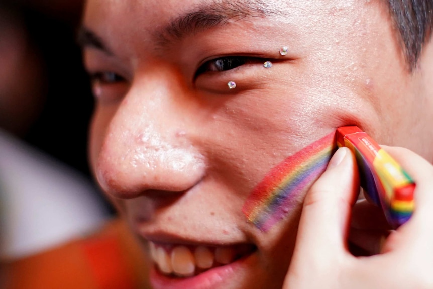 A rainbow is drawn on a man's face.