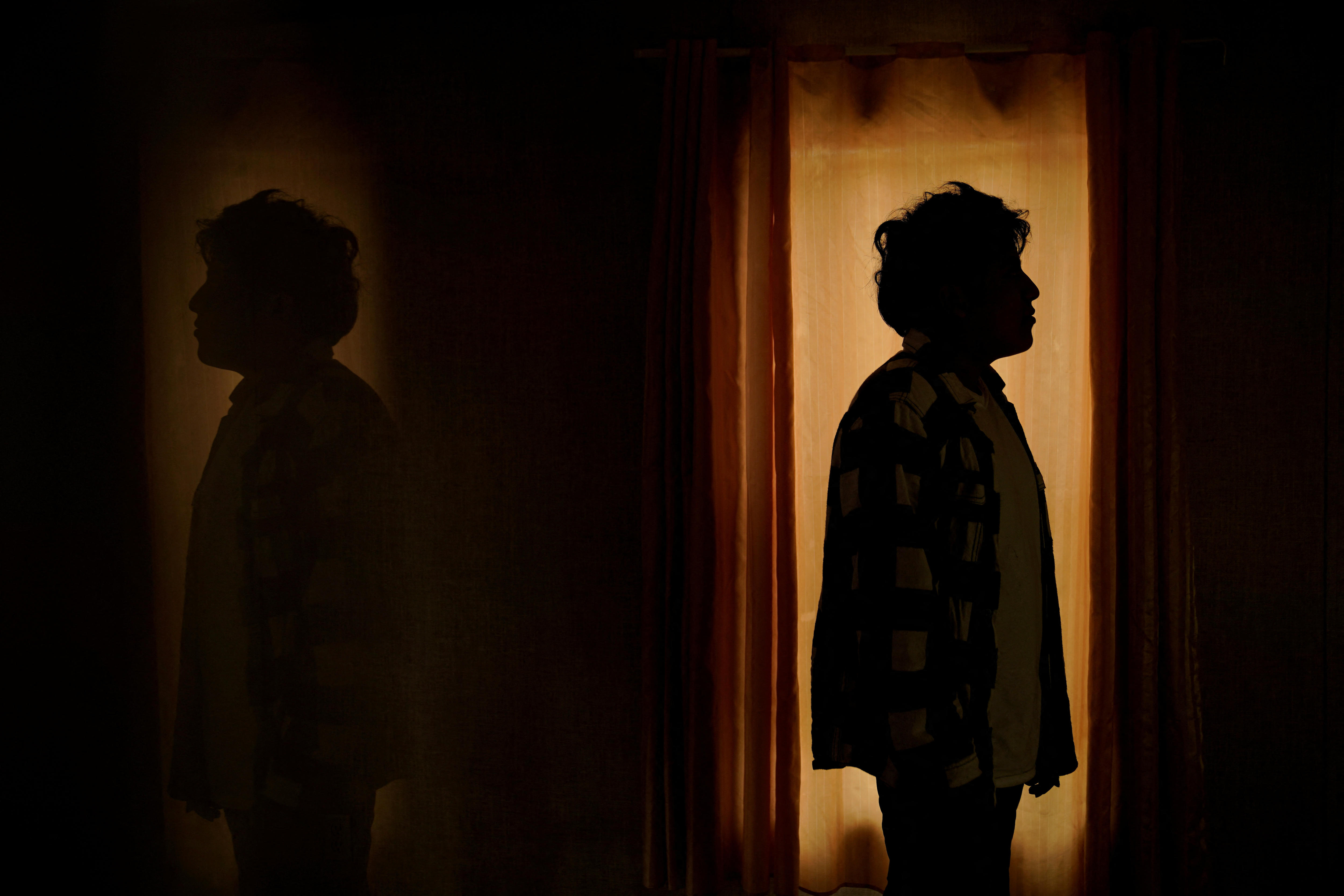 la silueta de una persona puede estar de lado mientras se para cerca de la luz de una ventana