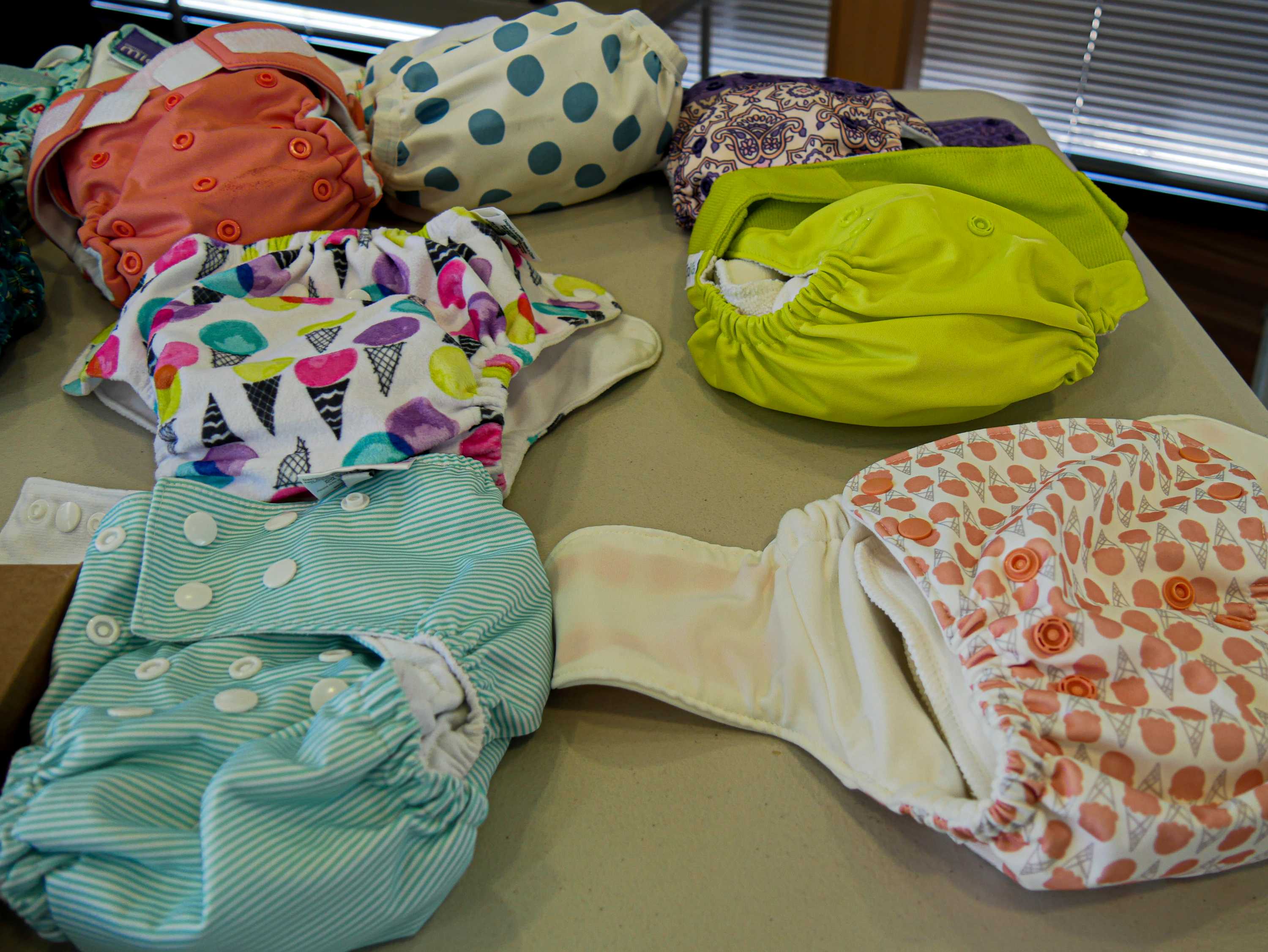 Several modern cloth nappies ranging in colour and style sitting on a table.