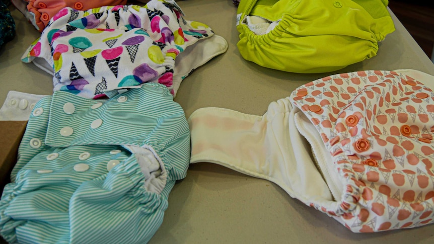 Several modern cloth nappies ranging in colour and style sitting on a table.