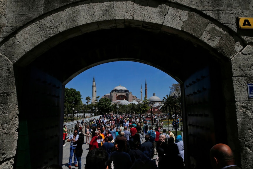 A view from underneath a bridge that shows crowds forming outside Hagia Sophia from a distance.