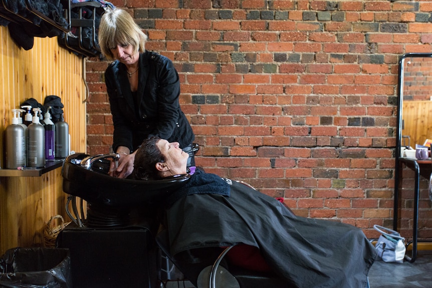 A client lying on a chair as she gets her hair washed.
