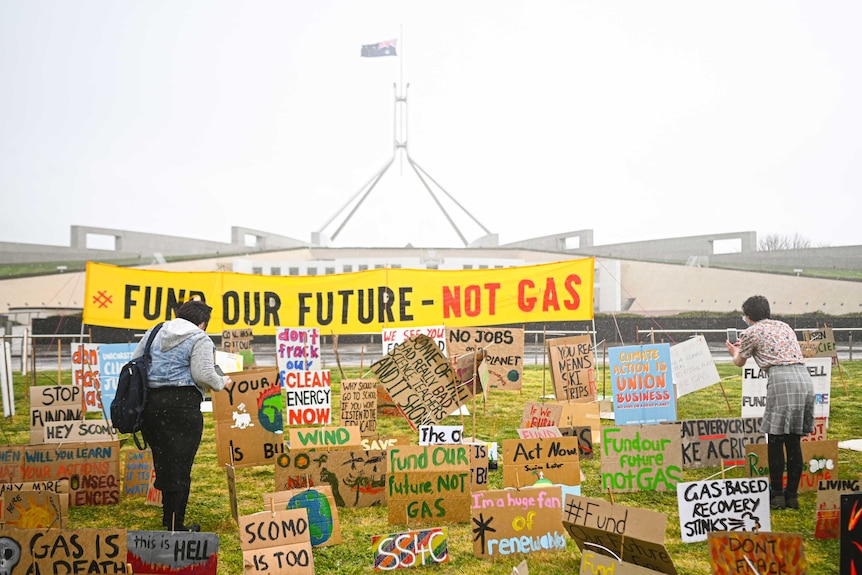 Between 50 and 100 placards are seen in front of Parliament House in Canberra, a banner reads: "Fund our future - not gas."