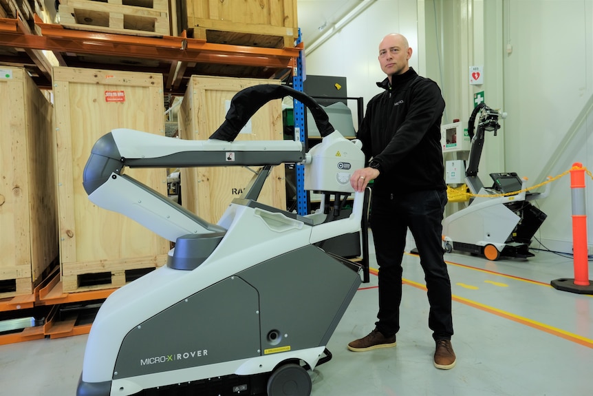 A man with a medical device on wheels in a warehouse