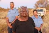A Warakurna resident stands with police officers Wendy Kelly and Revis Ryder.