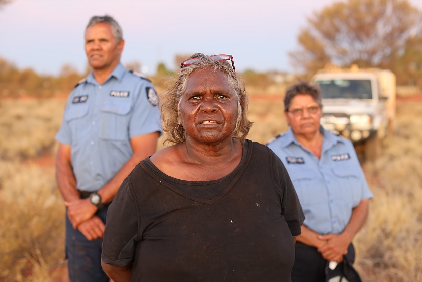 A Warakurna resident stands with police officers Wendy Kelly and Revis Ryder.