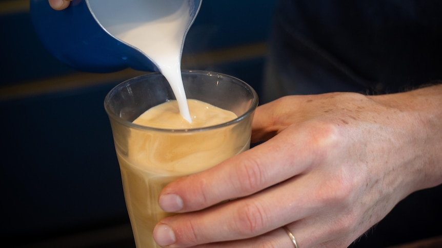 pouring milk into a coffee