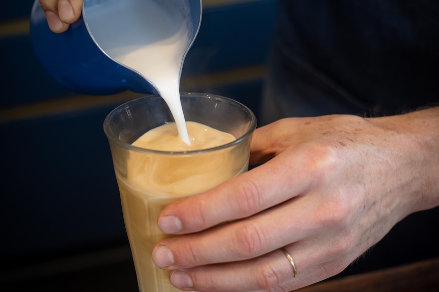 pouring milk into a coffee