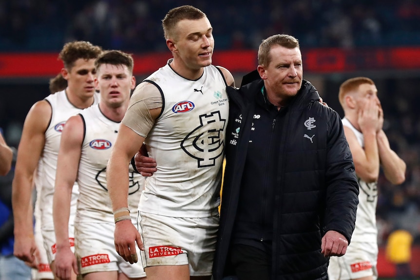 Patrick Cripps and Michael Voss walk off the ground with an arm around each other