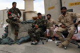 Afghan security forces sit at Bagram air base, one holding a weapon.