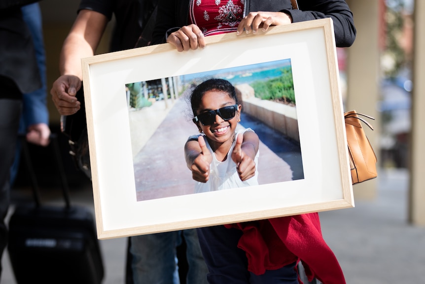 A picture of a woman holding a framed photo of a little girl