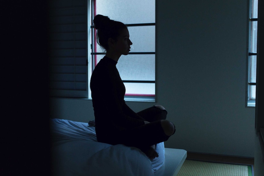A woman sits on the edge of a bed