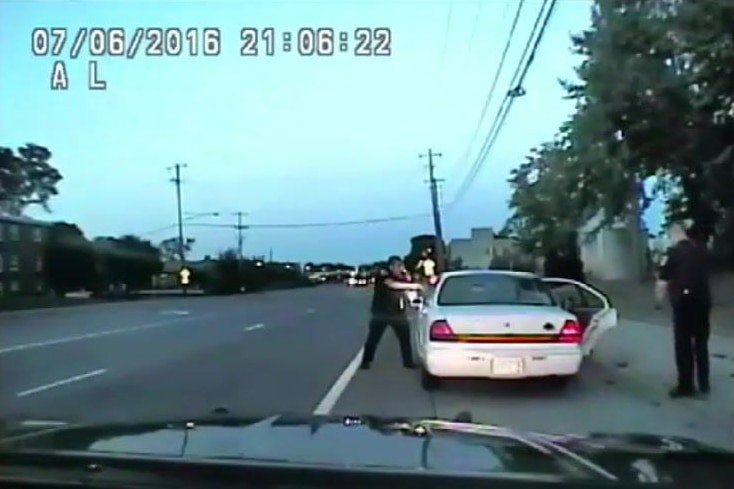 Police officers with their guns drawn next to a car