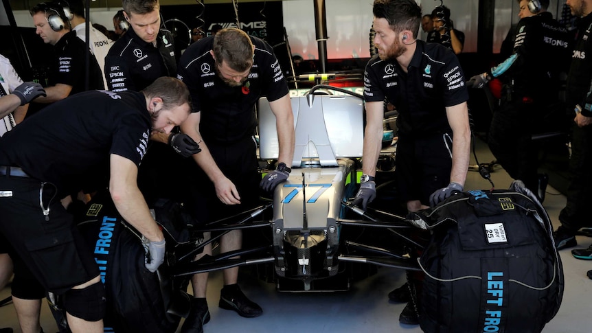 Team members of Mercedes working on their car.
