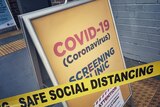 A yellow A-frame sign that says COVID-19 screening clinic.