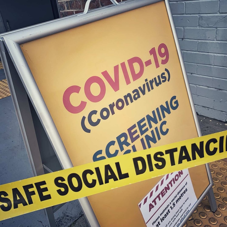 A yellow A-frame sign that says COVID-19 screening clinic.