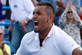 A male tennis player drops his racquet and screams out as he celebrates winning a match.