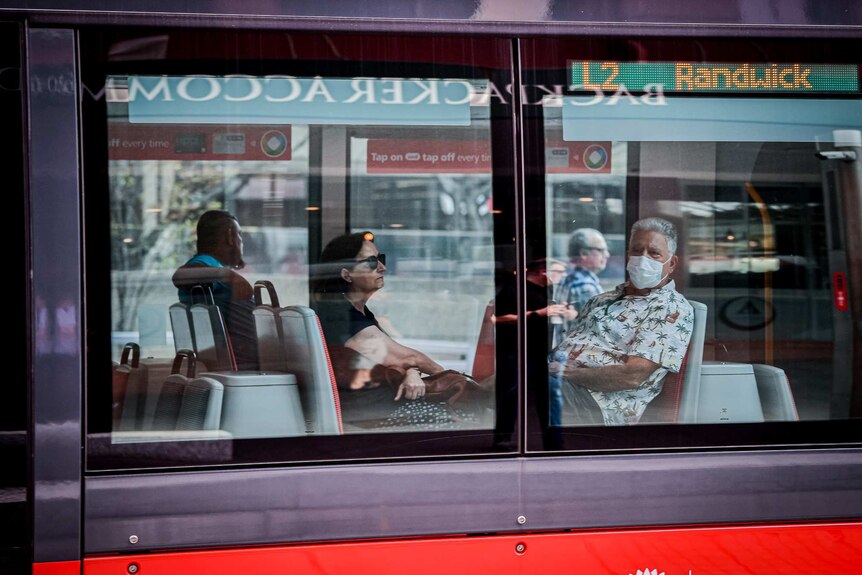 A man wearing a mask and a woman on a light rail tram