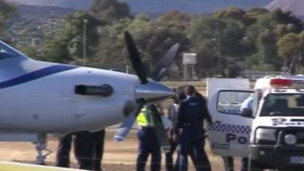 Police escorted Cameron Mansell (with jacket over his head) onto the plane at Kalgoorlie