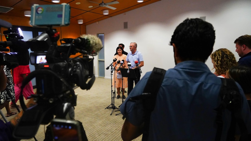 A zoomed out shot of the Prime Minister and Chief Minister at a press conference, surrounded by journalists