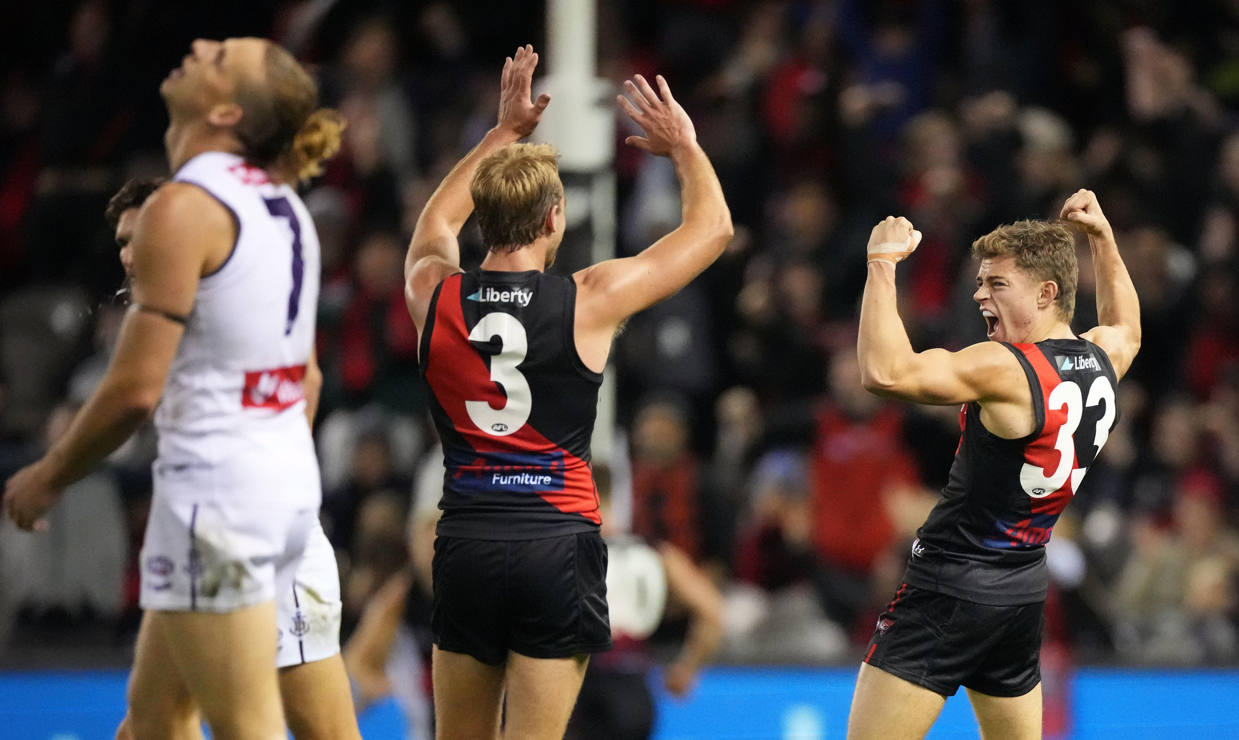 Brayden Ham flexes his muscles and yells as Essendon teammate Darcy Parish tries to high-10 him during an AFL game.